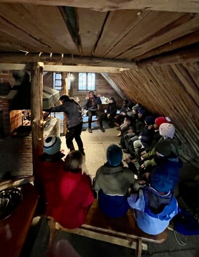 Kinder in einer Hütte vor einem Lagerfeuer.